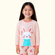 Child wearing a pink pajama set with a bunny design on a white background