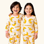 Two children wearing pajamas with banana pattern on a white background