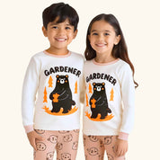 Two children wearing matching 'Gardener'-themed pajamas with bear graphics on a plain background.