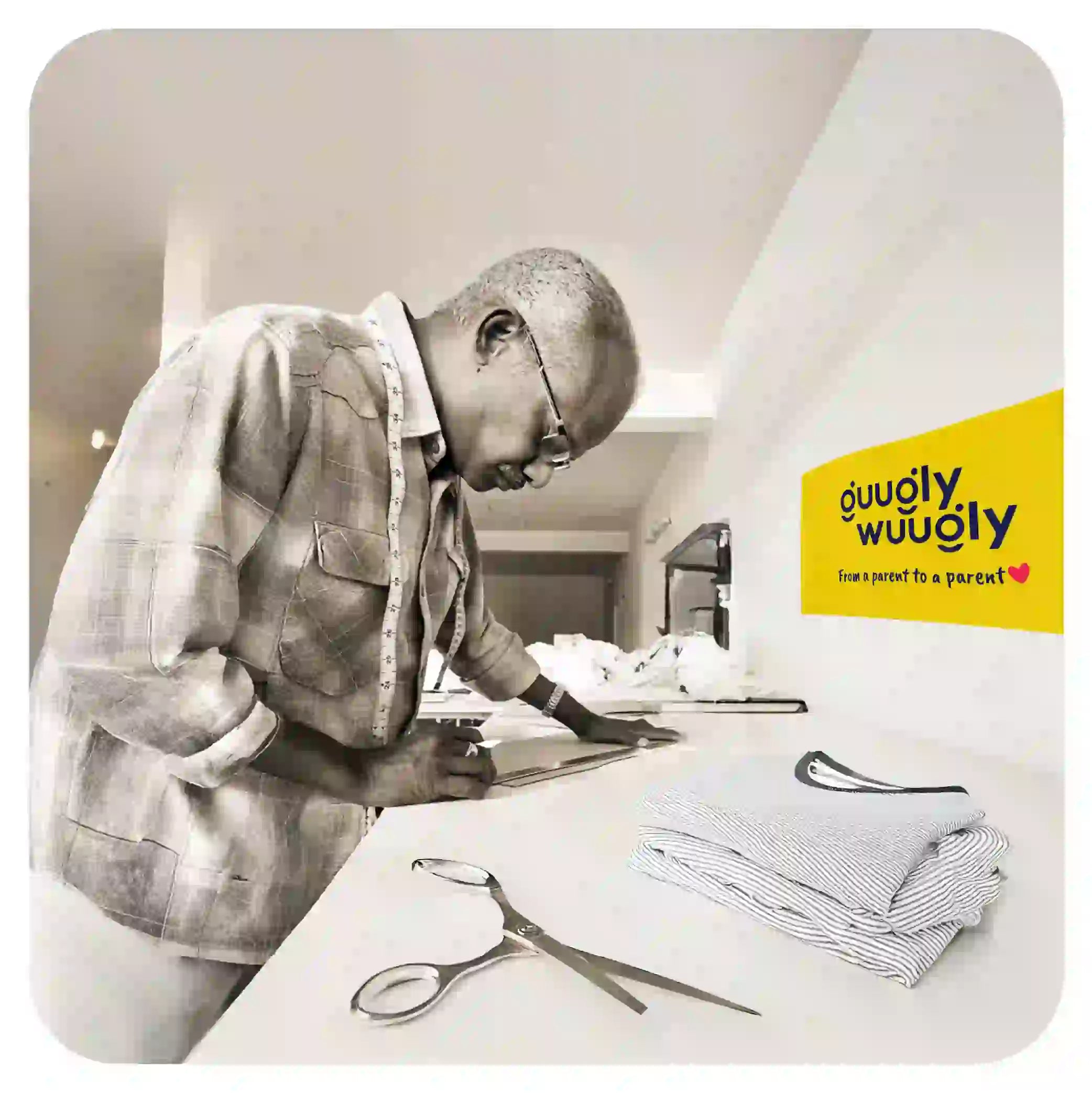 Person working with fabric and scissors on a table, with 'Guugly Wuugly' branding.