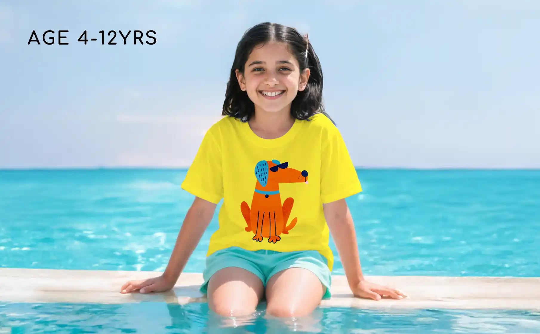 Girl in a yellow shirt with a dog graphic sitting by a pool.