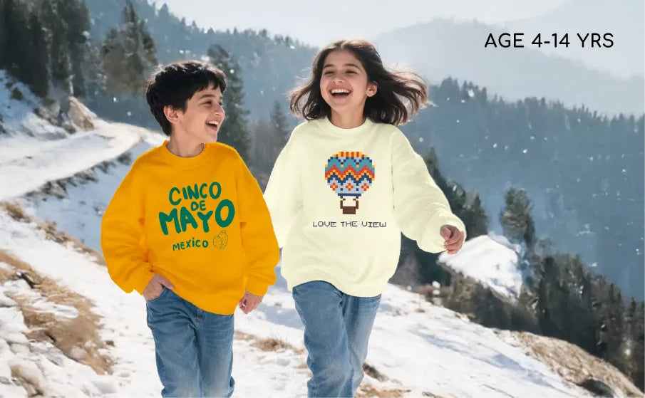 Two children wearing colorful sweatshirts with text and graphics, standing on a snowy landscape.